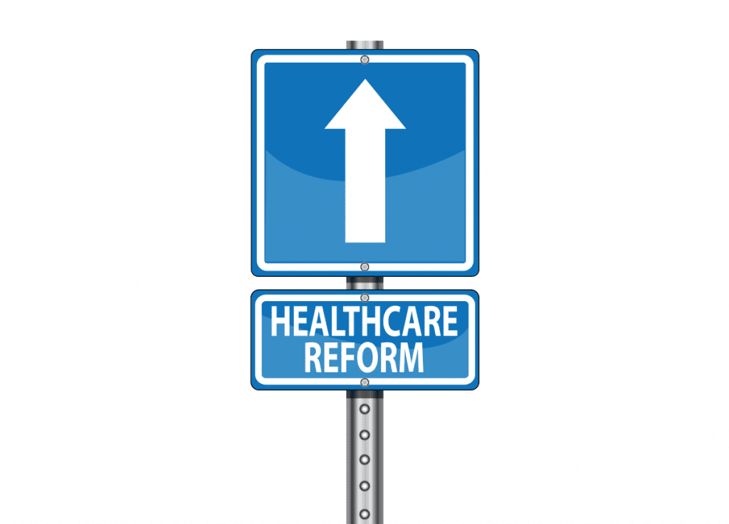 A blue road sign with a large white upward arrow above a smaller sign that reads Healthcare Reform, symbolizing progress or movement forward in healthcare reform.