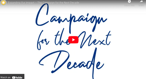 Video thumbnail with blue handwritten text reading Campaign for the Next Decade on a white background. A red play button is in the center, with a sun logo in the top left corner.
