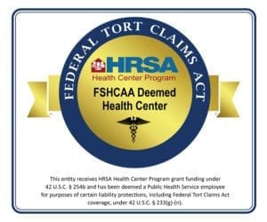 A circular blue and gold seal reads Federal Tort Claims Act. Inside, the HRSA Health Center Program logo and “FSHCAA Deemed Health Center” are shown above a caduceus symbol and explanatory text about legal liability protection.